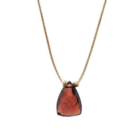 A gold cord necklace with a teardrop-shaped garnet pendant on a plain white background.