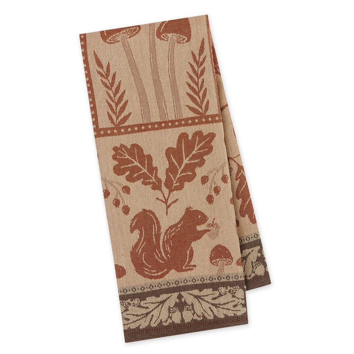 A rectangular kitchen towel with a rustic woodland pattern featuring a squirrel, oak leaves, mushrooms, and botanical motifs in brown and rust tones on a beige background, shown against a plain white background.