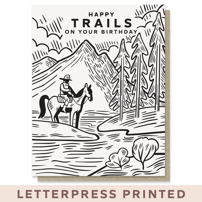 Birthday card with a black and white illustration of a cowboy on a horse in a mountainous landscape, with 'Happy Trails on Your Birthday' text.