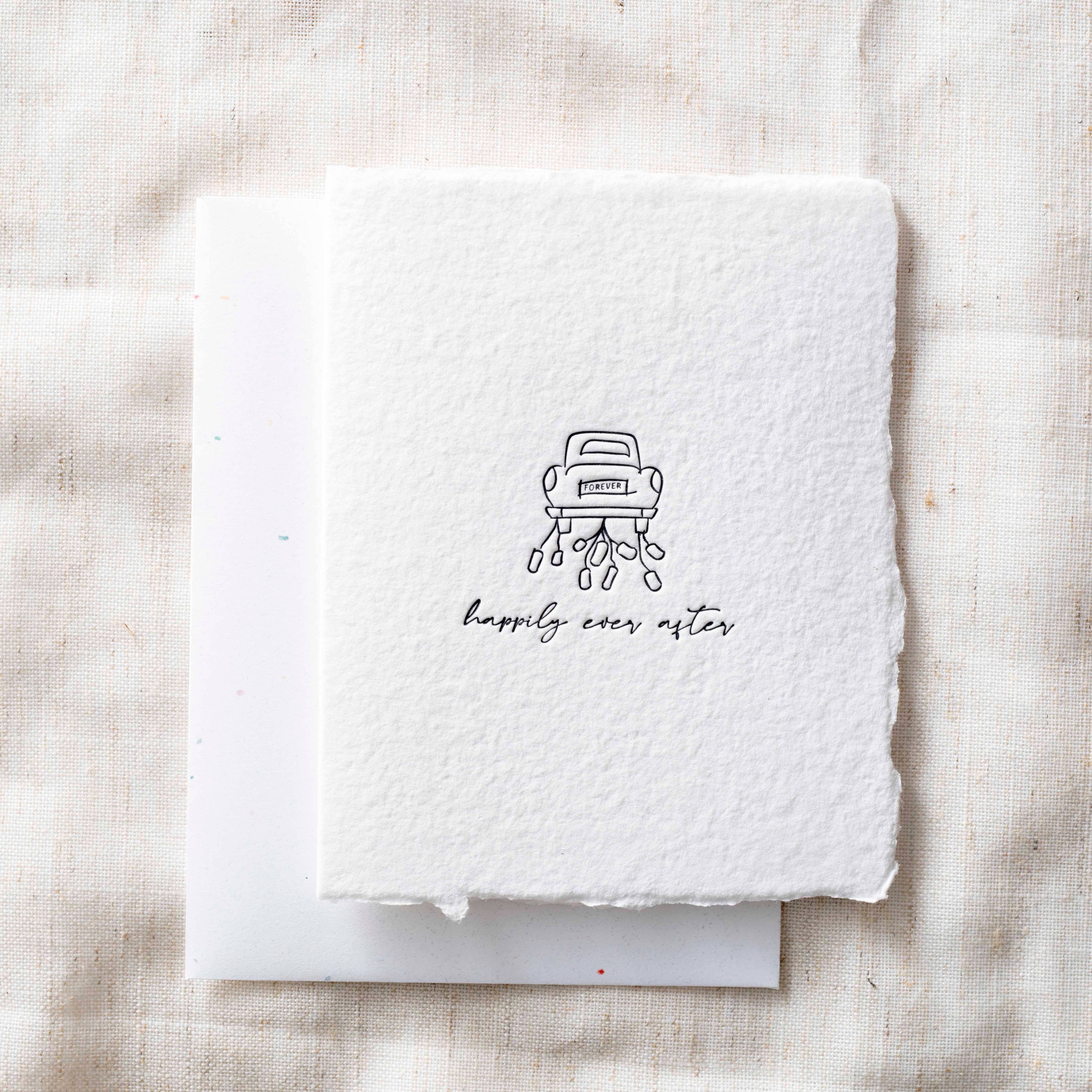 White card with a black illustration of a car and 'happily ever after' text on a textured beige background