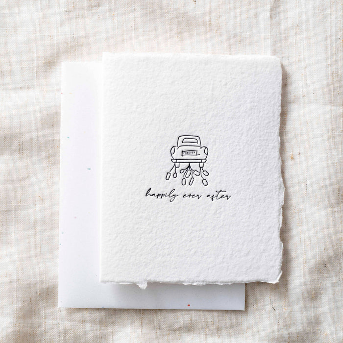 White card with a black illustration of a car and 'happily ever after' text on a textured beige background