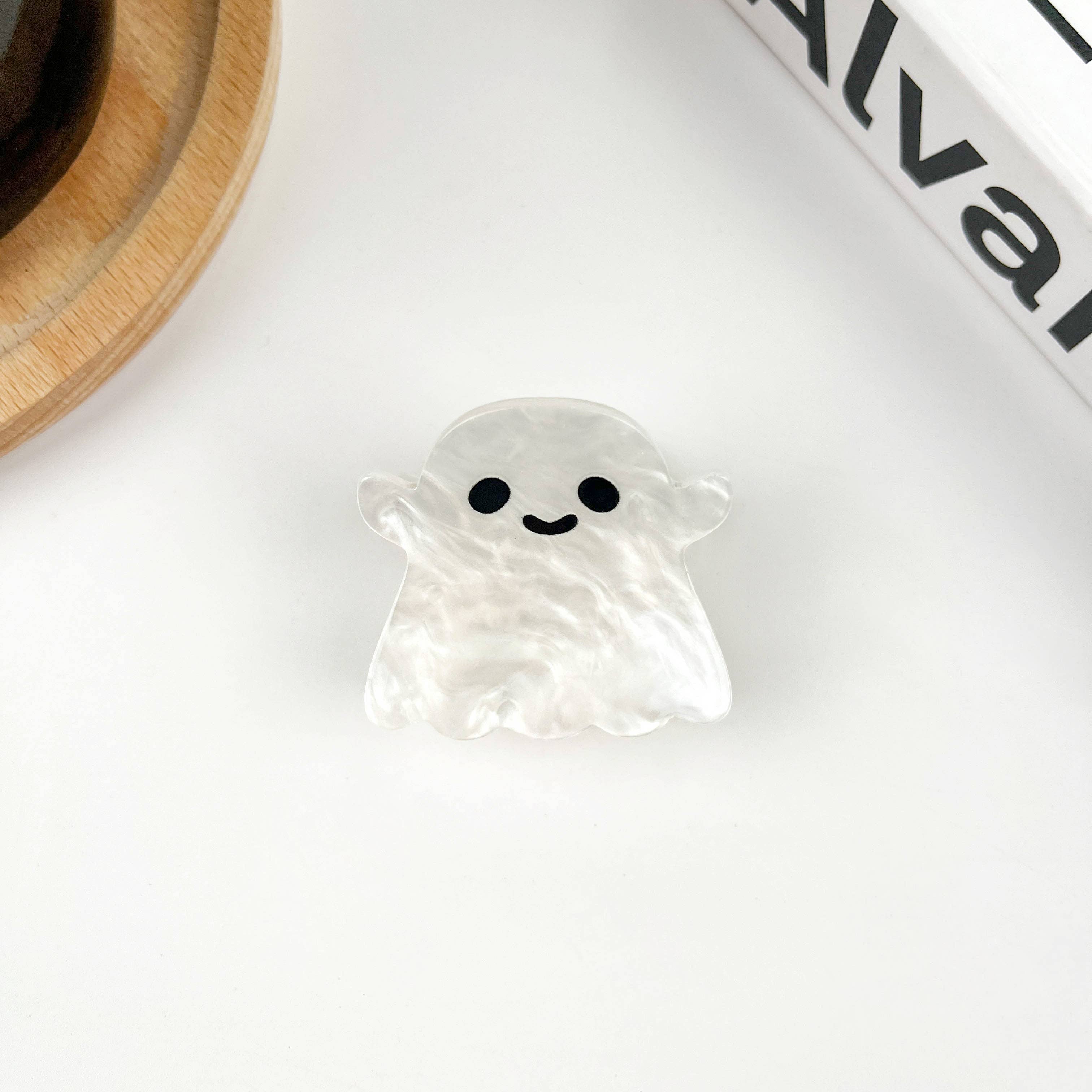 Ghost-shaped hair clip with a smiling face on a white surface