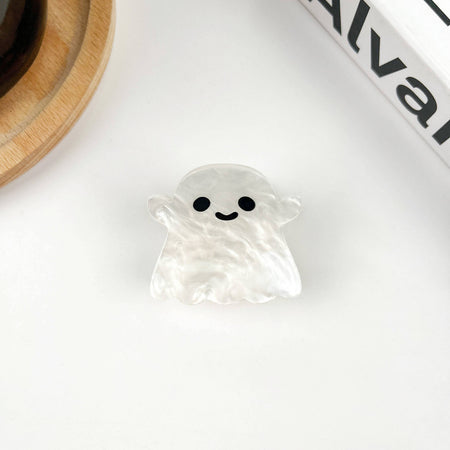Ghost-shaped hair clip with a smiling face on a white surface