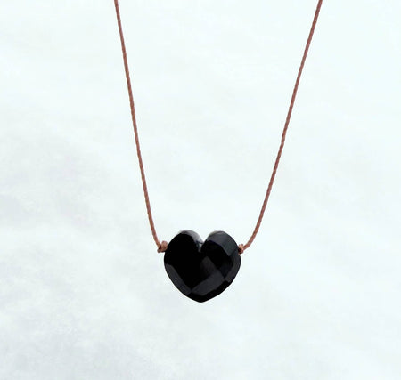 Black heart-shaped pendant on a thin brown cord against a white background