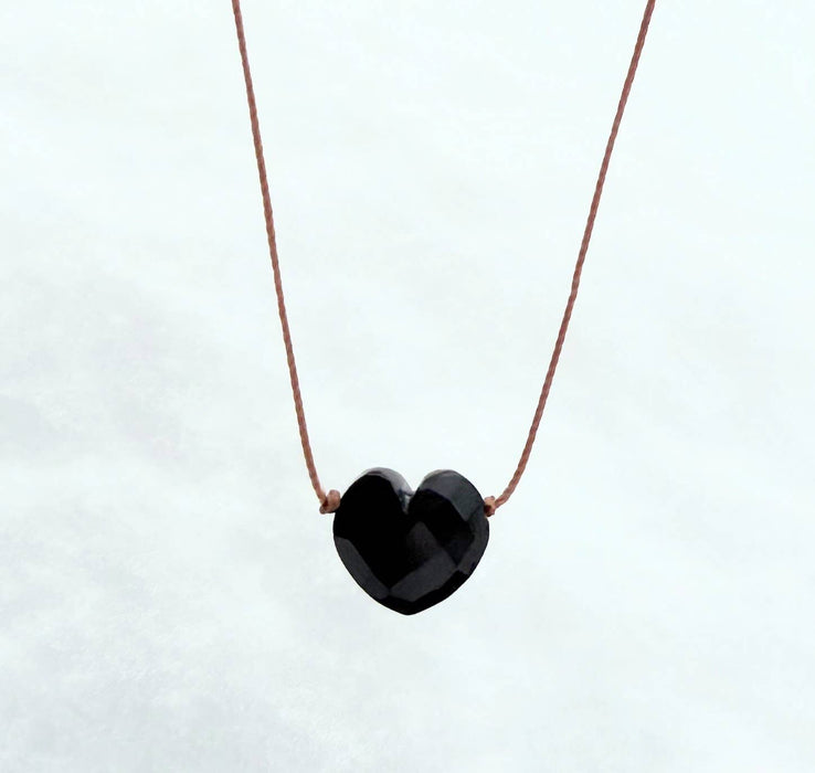 Black heart-shaped pendant on a thin brown cord against a white background