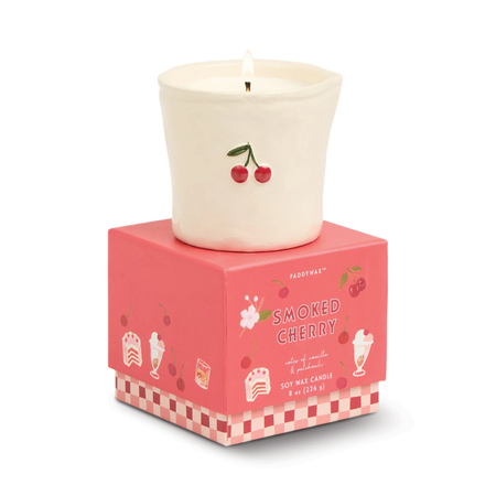 Candle with cherry design on a pink box labeled 'Smoked Cherry' on a white background