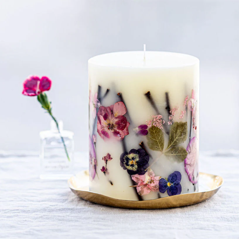 Decorative candle with pressed flowers on a white surface