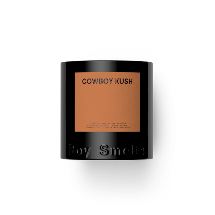Candle with 'Cowboy Kush' label and 'Boy Smells' branding on a white background