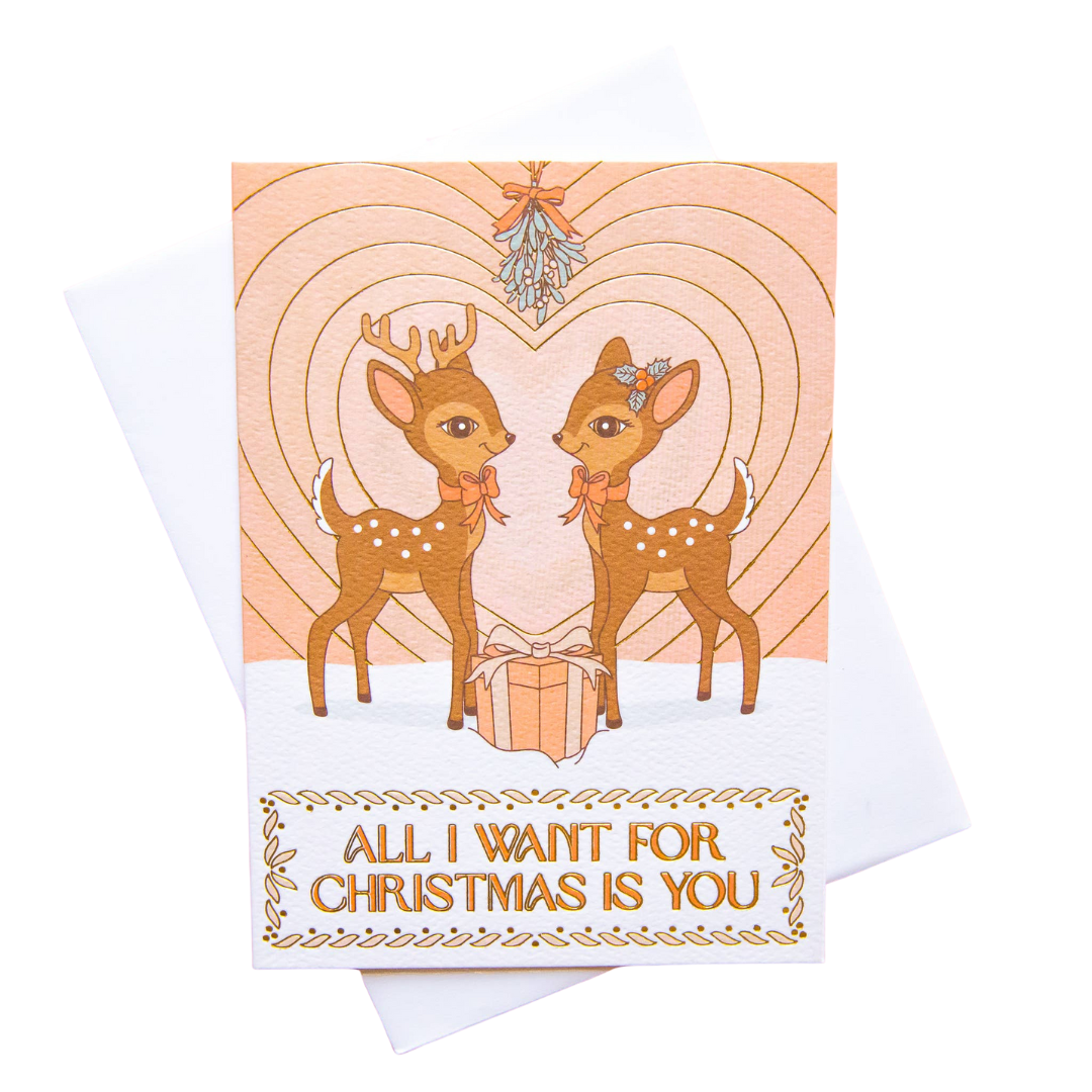 Greeting card with two deer holding a gift, text 'All I Want for Christmas is You', on a white background.