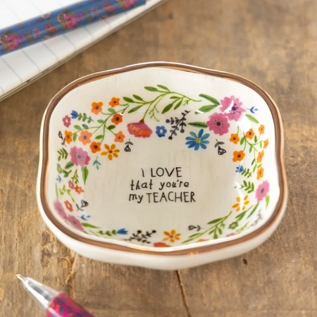 Decorative dish with floral design and 'I love that you're my teacher' text on a wooden surface.