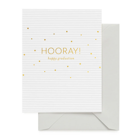 A white letterpress graduation card with the words 'Hooray!' and 'Happy Graduation' in gold, along with small gold stars on the front. The card is blank inside for a personal message and comes with a matching envelope.