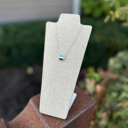 Necklace on a gray stand with a blurred outdoor background