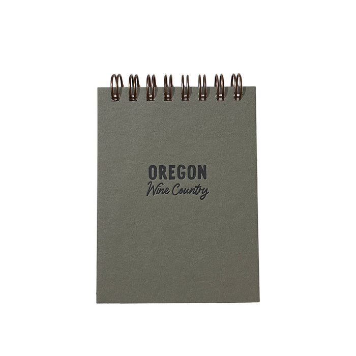 Small green notebook with 'Oregon Wine Country' text on a white surface