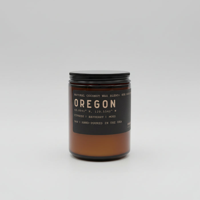 Candle jar labeled 'Oregon' with a black lid on a white background