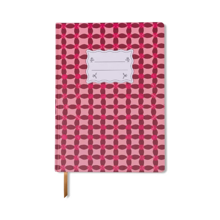 A hardcover notebook with a pink and red geometric pattern, featuring a blank white label on the front cover and a brown ribbon bookmark hanging from the bottom edge, set against a plain white background.