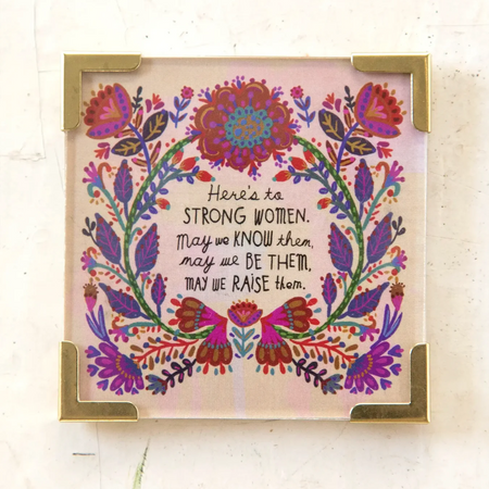 A colorful refrigerator magnet with a floral design and a quote about strong women.