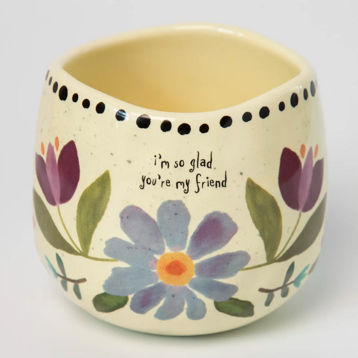 Ceramic pot with floral design and text on a white background