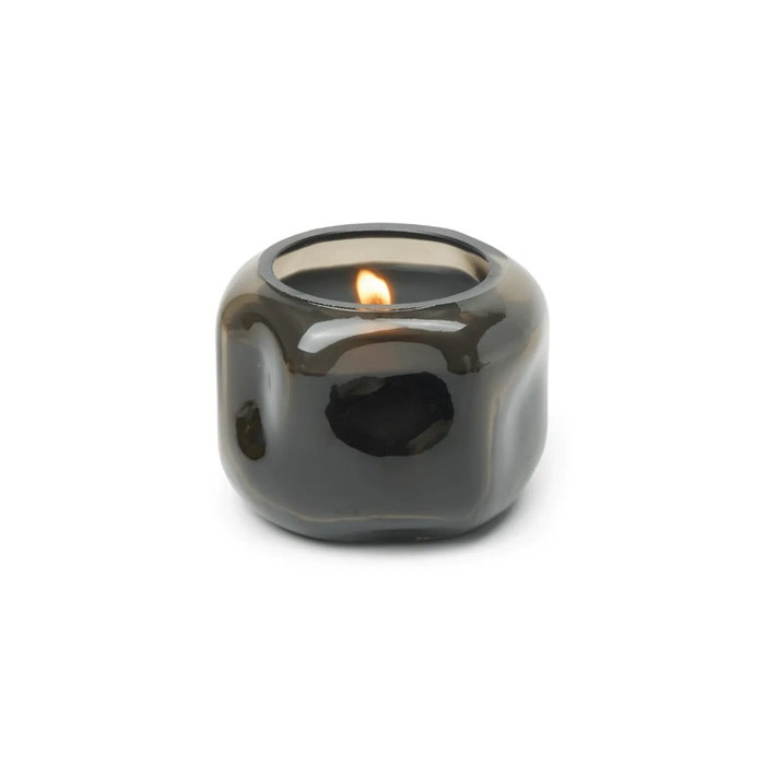 Smoky gray candle holder with a lit candle on a white background