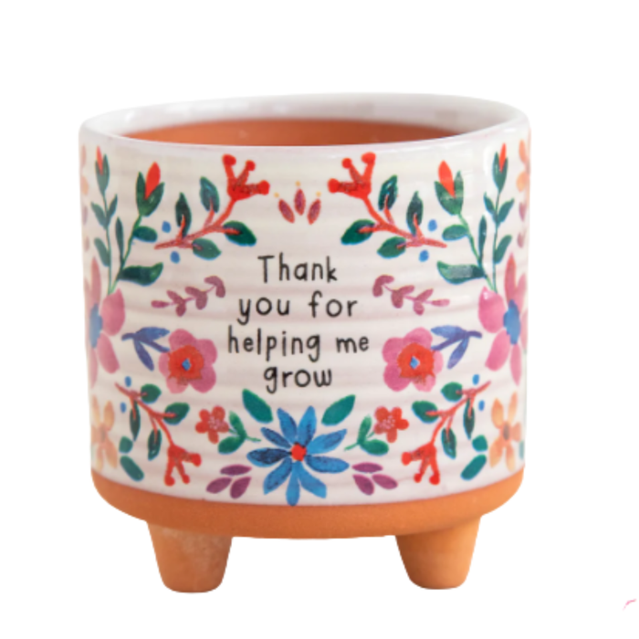Ceramic pot with floral design and text on a white background