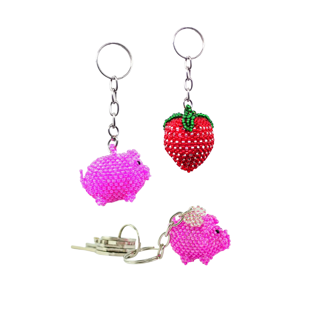 3 seed bead keychains featuring a red strawberry, a pink pig, and a pink pig with wings