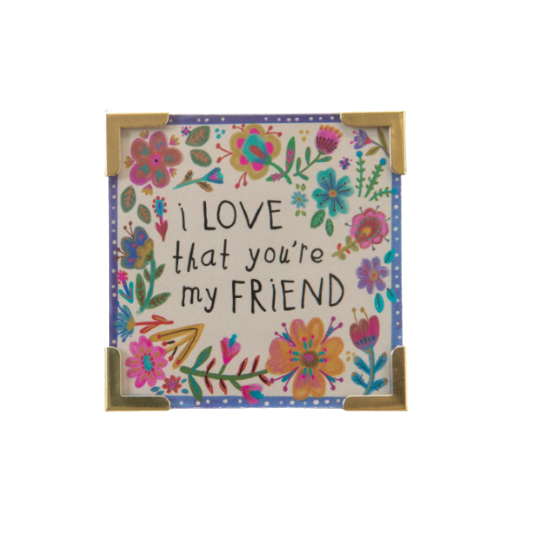 Decorative sign with floral design and text 'I love that you're my friend' on a white background