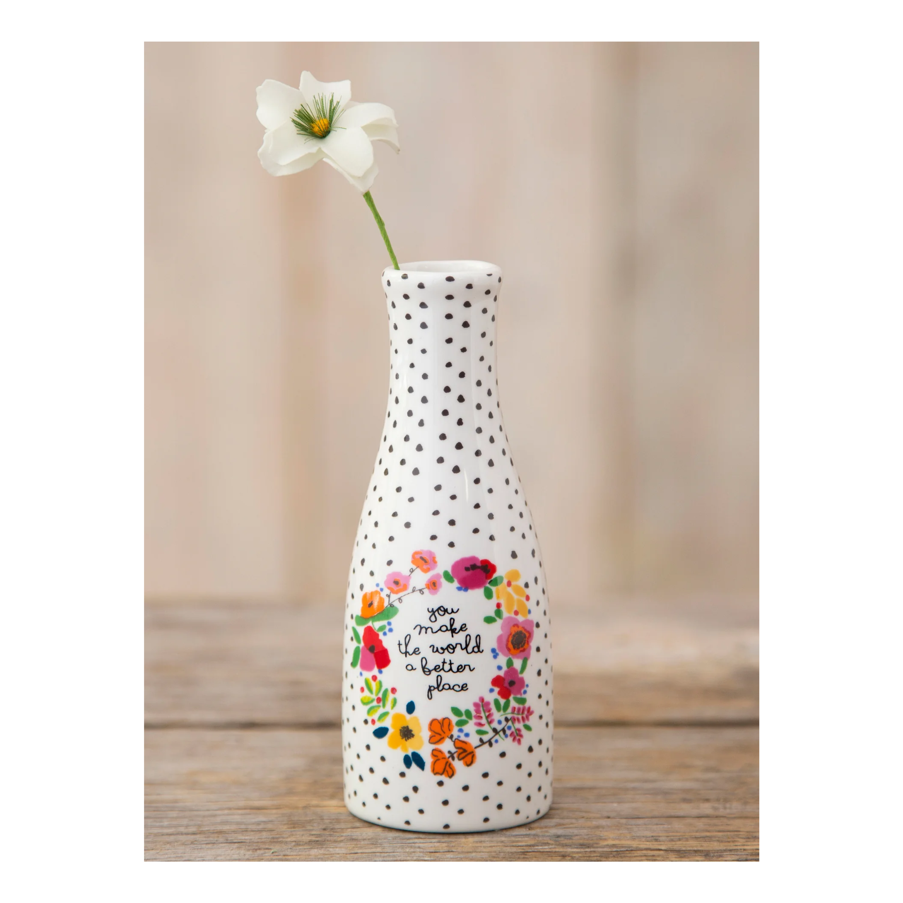 Decorative bud vase with floral design and text thats reads "you make the world a better place" on a wooden surface