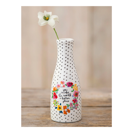 Decorative bud vase with floral design and text thats reads "you make the world a better place" on a wooden surface