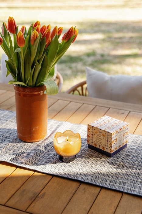 Vase of tulips on a wooden table with a candle and decorative box.