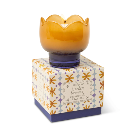 Yellow wax candle in a decorative box with floral pattern on a white background