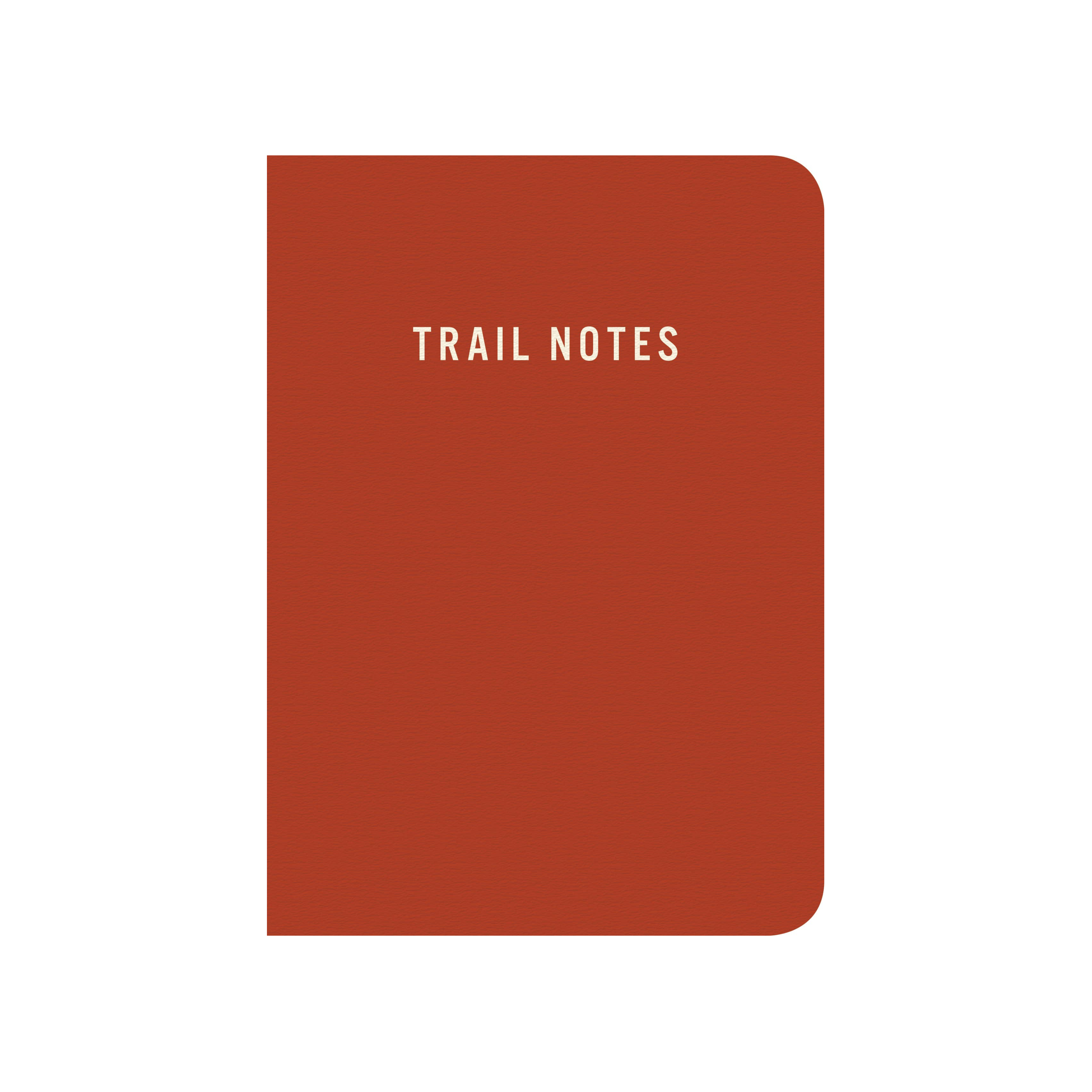 A rust-red hardcover notebook with rounded corners and the words 'TRAIL NOTES' printed in white at the top center, shown on a plain white background.