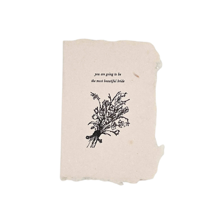 A square beige paper card with torn edges, featuring a black ink illustration of a bouquet of wildflowers and the printed text 'you are going to be the most beautiful bride' on a plain white background.