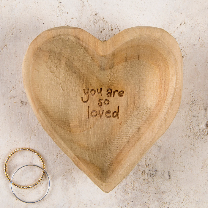 Heart-shaped wooden trinket dish with ‘you are so loved’ lettering, pictured beside two rings.”