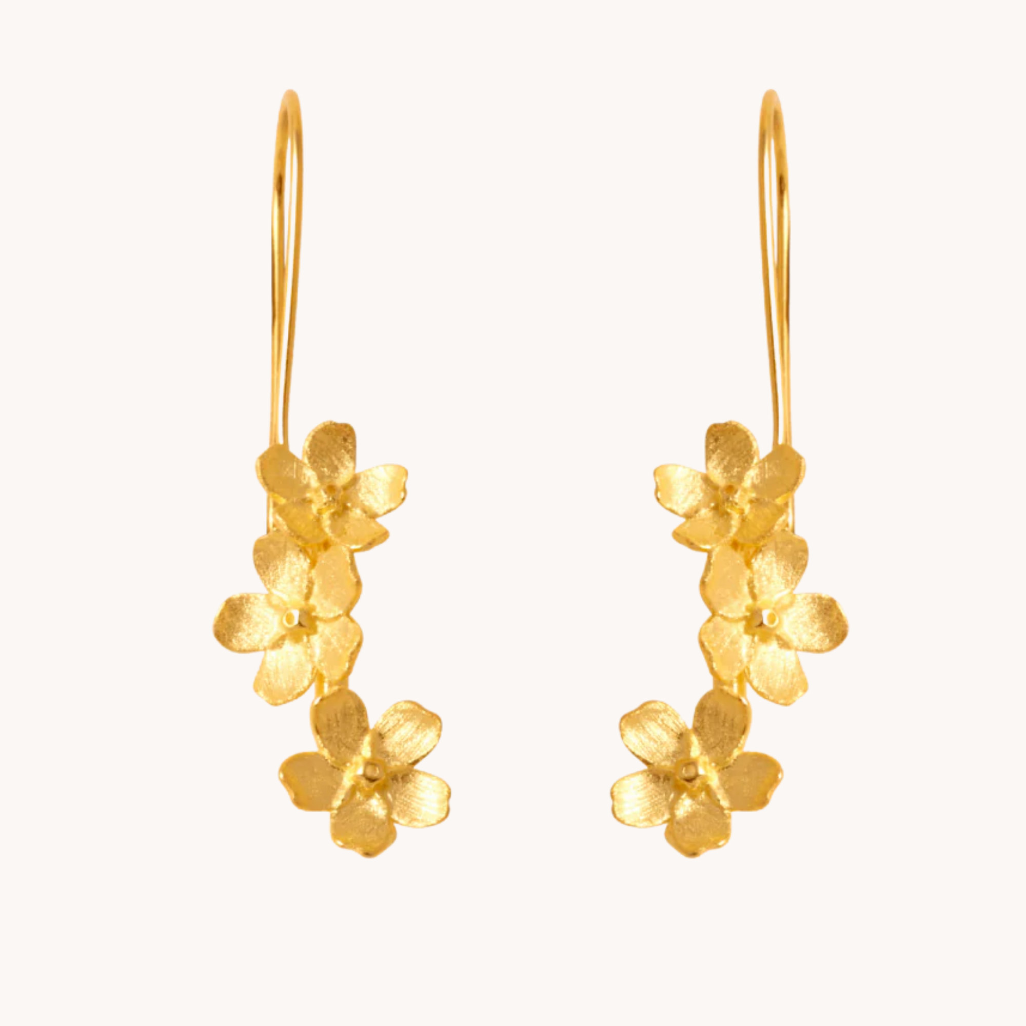 Gold floral earrings on a white background