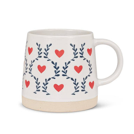 White mug with red heart and blue leaf pattern on a white background