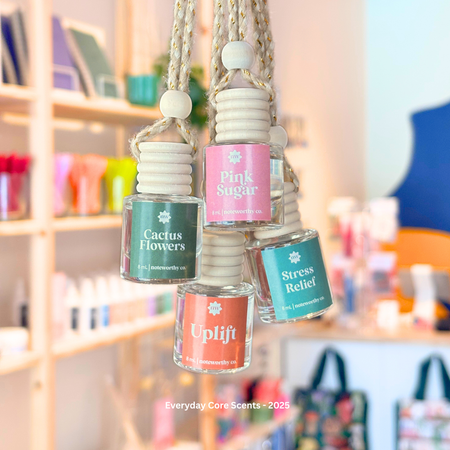 small bottles of essential oil car diffusers hanging by strings with visible labels in a store setting.