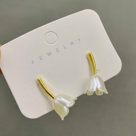 Flower-shaped earrings on a jewelry card with a gray background