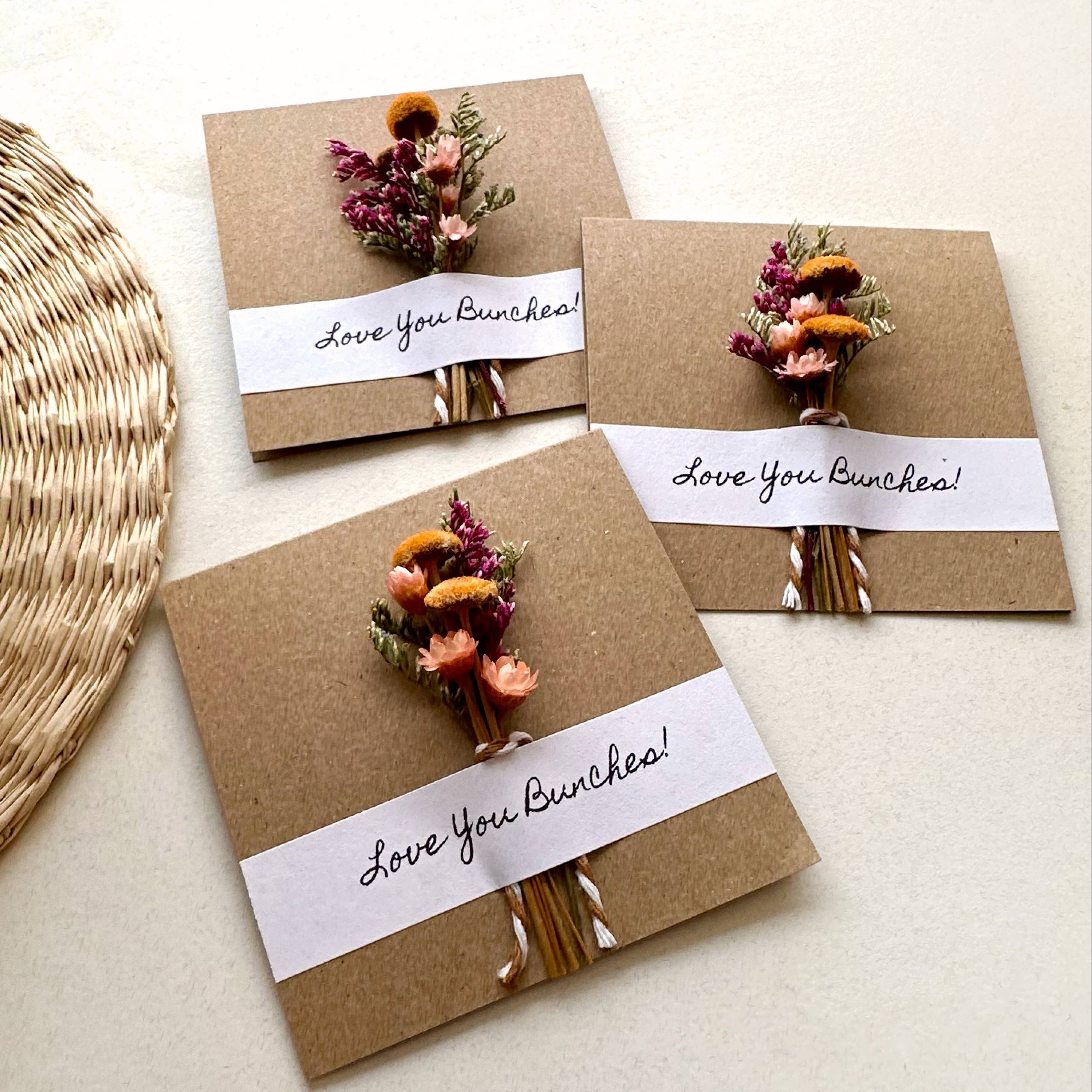 Three brown paper cards with dried flowers and 'Love You Bunches!' text on a light background.