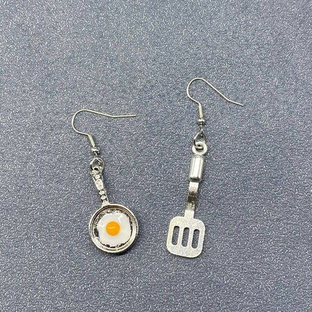 Earrings with frying pan and spatula design on a gray background
