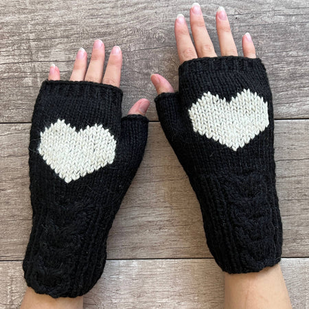 Black fingerless gloves with heart patterns on a wooden surface