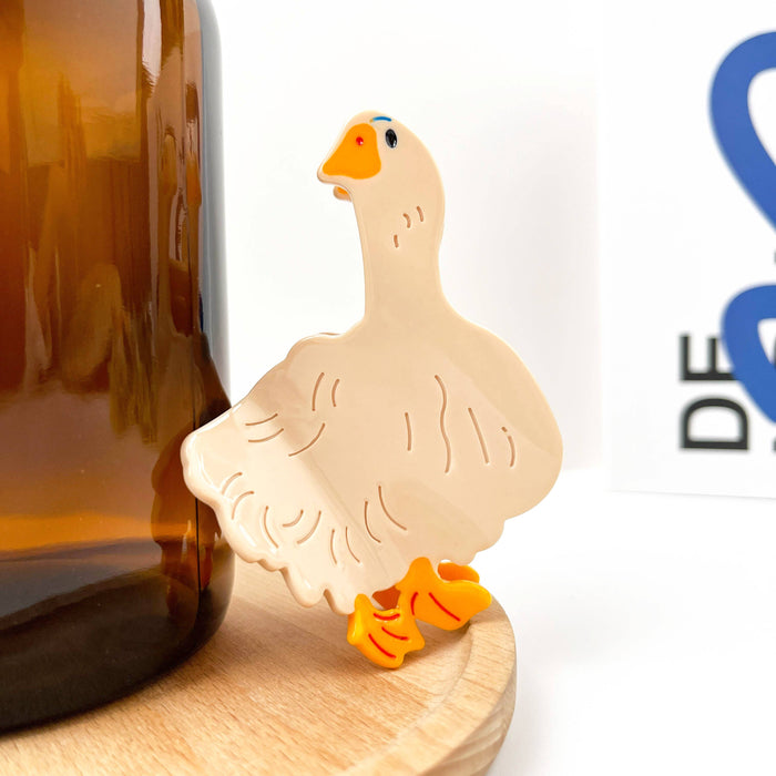 Decorative goose-shaped hair clip on a wooden surface with a blurred background