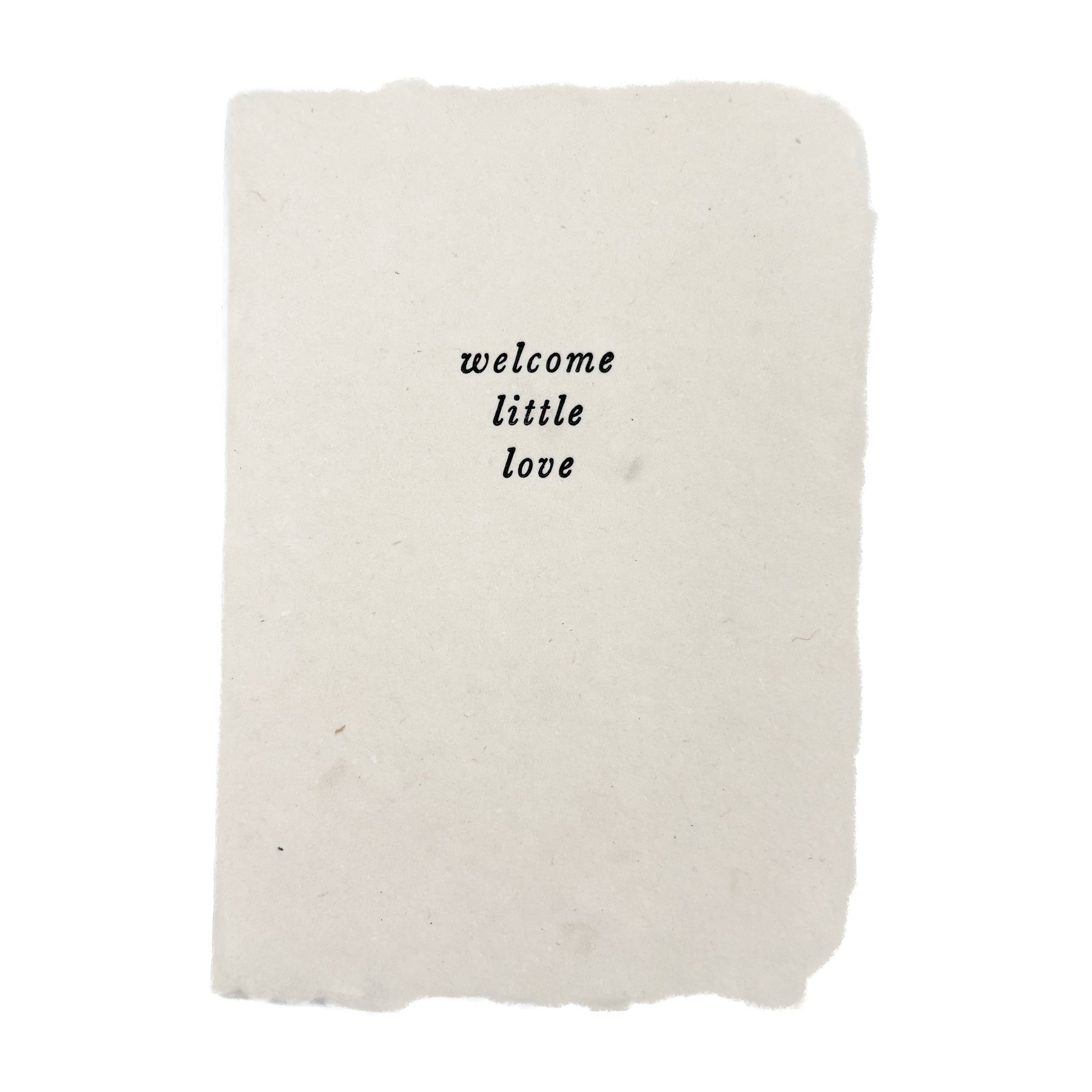 White blanket with 'welcome little love' text on a white background