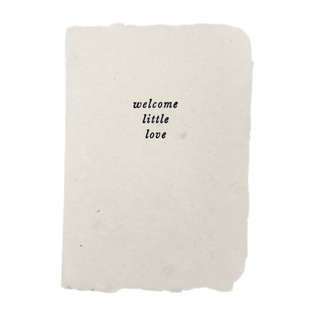 White blanket with 'welcome little love' text on a white background