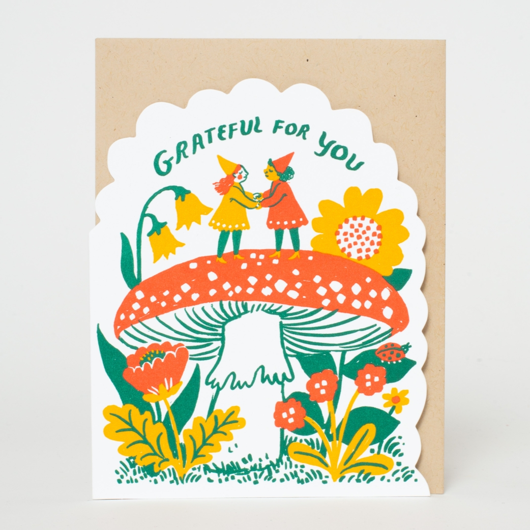 A greeting card with a colorful illustration of gnomes, flowers, and a mushroom with the text 'grateful for you'.