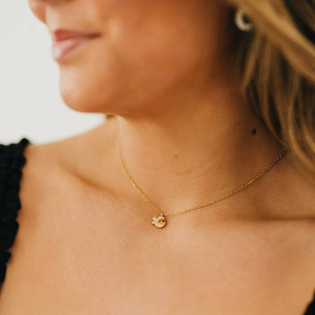 Close-up of a woman wearing a gold necklace with a small pendant.
