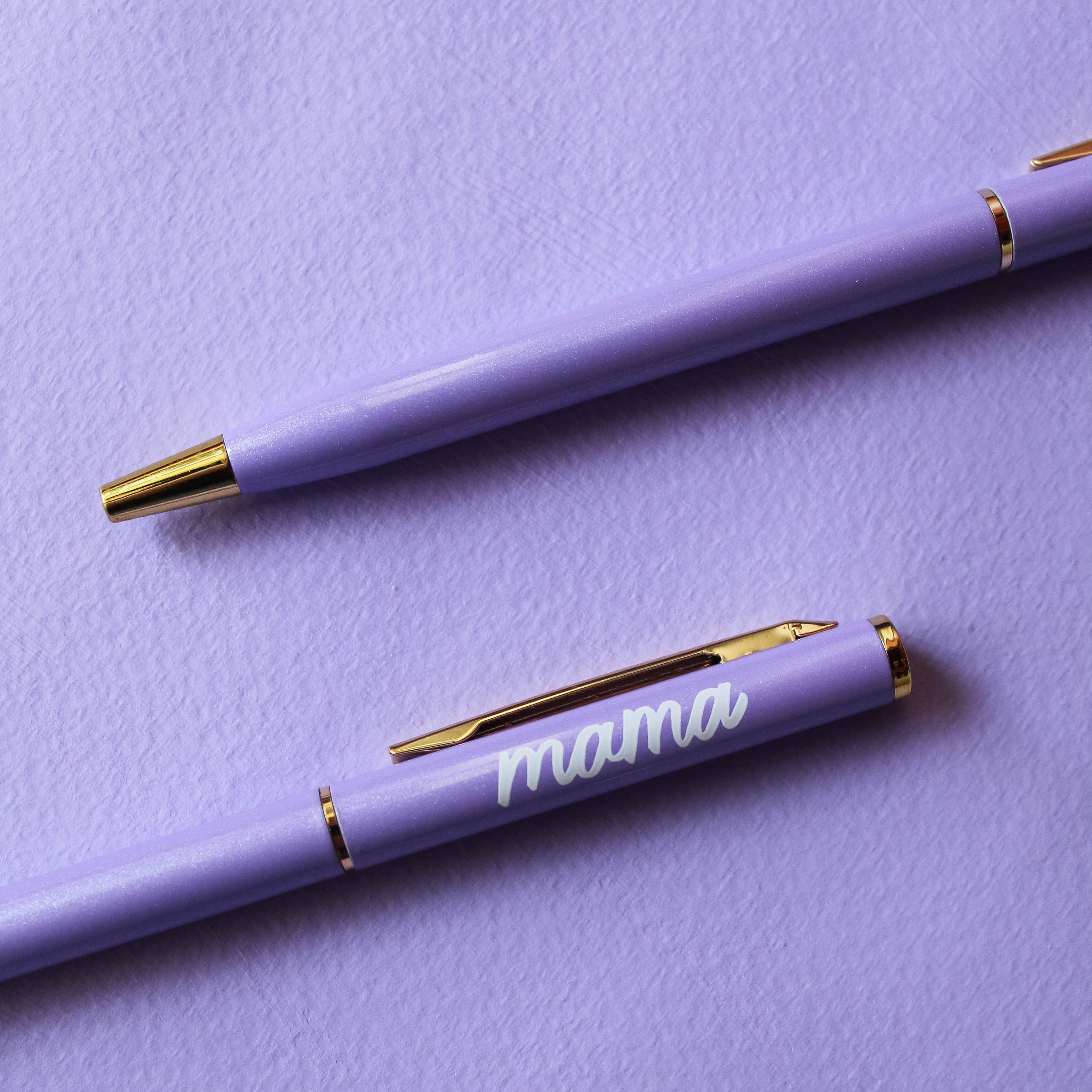 Two purple pens on a purple background, one with 'mama' engraved.