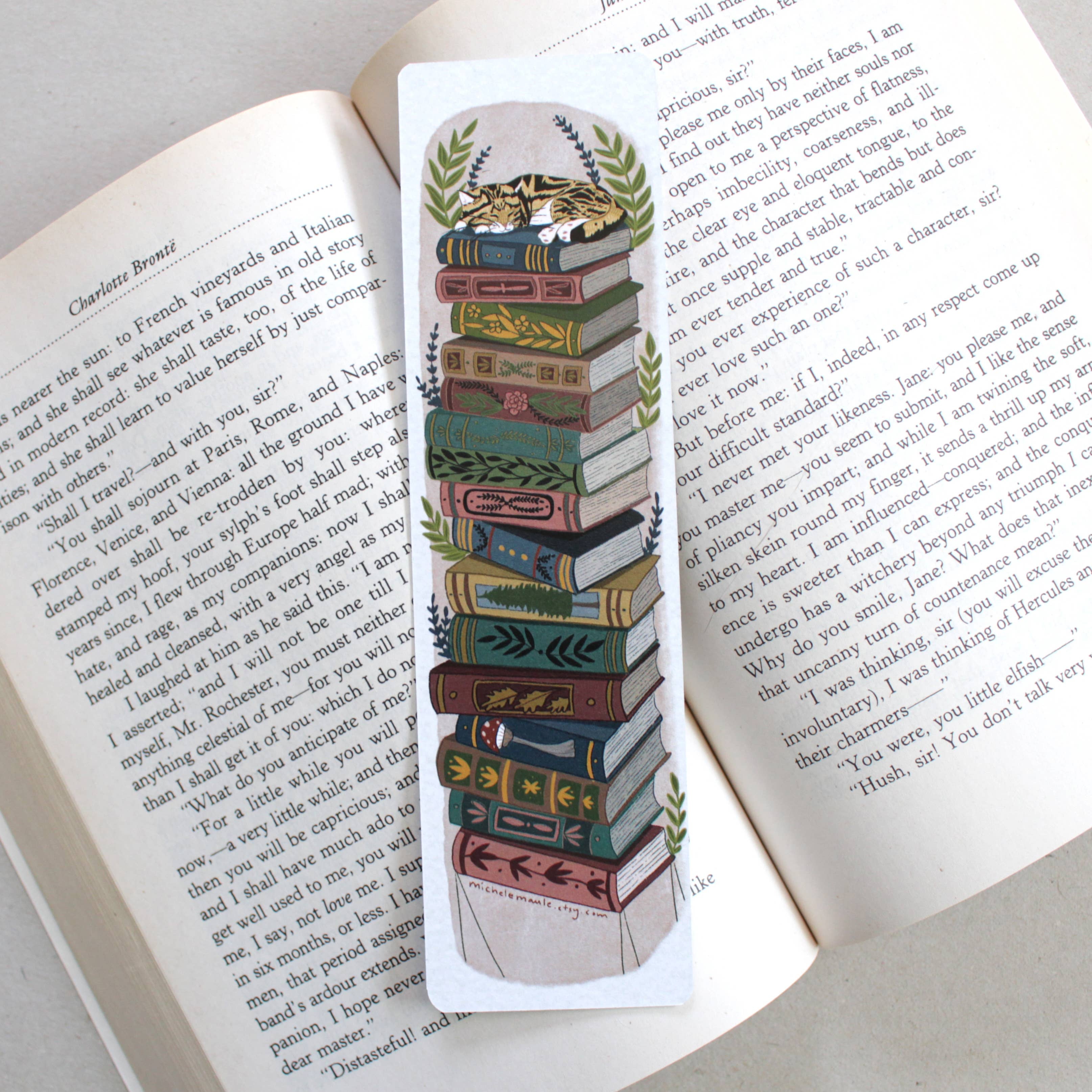 Decorative bookmark with a stack of books and a cat design on an open book