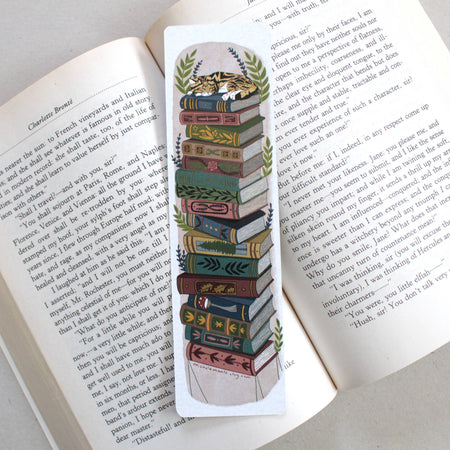 Decorative bookmark with a stack of books and a cat design on an open book