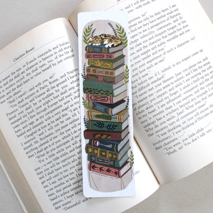 Decorative bookmark with a stack of books and a cat design on an open book