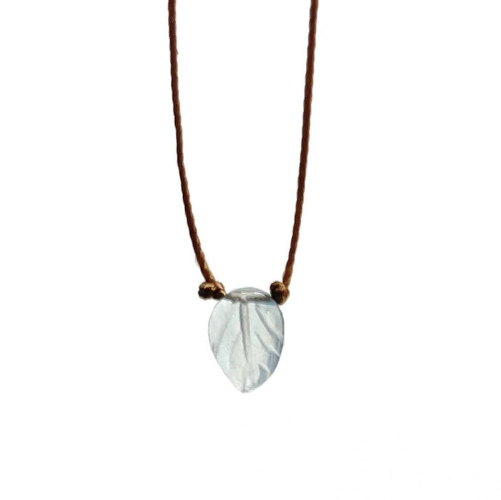 A leaf-shaped pendant necklace made of a pale translucent stone, suspended from a thin brown cord with small gold beads, shown against a plain white background.