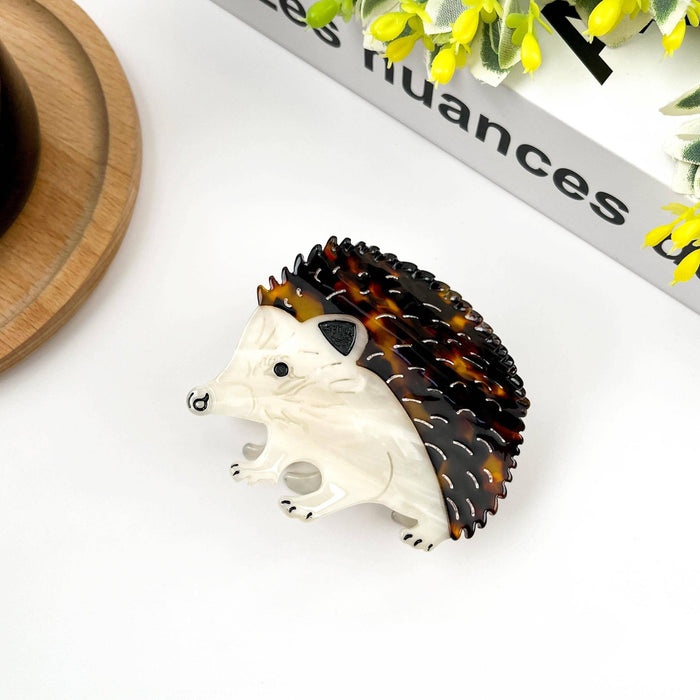 Hedgehog-shaped hair clip with tortoiseshell design on a white surface